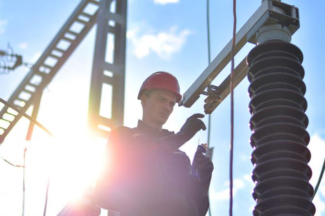 A worker in a red hardhat working at an electrical plant.